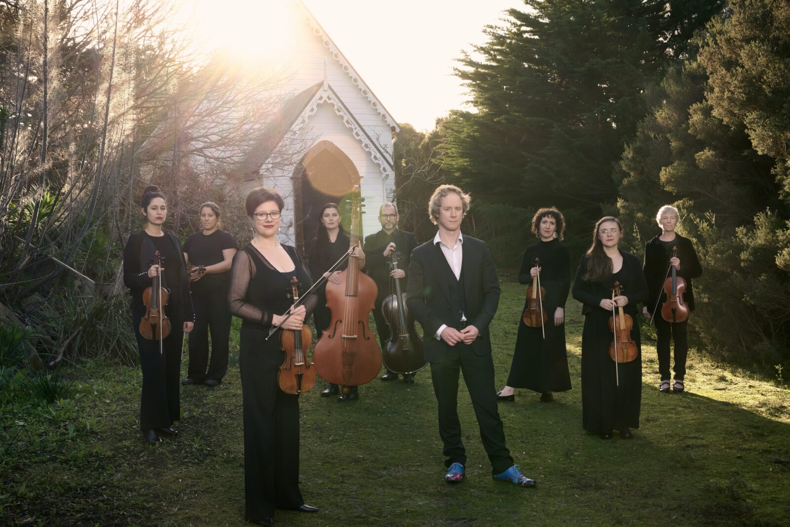 A group of musicians stand in front of an old wooden church