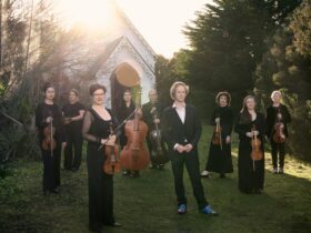 A group of musicians stand in front of an old wooden church