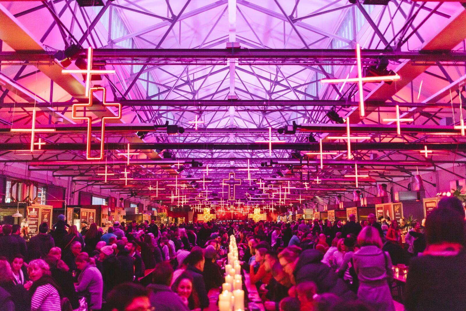 Under neon crosses and candlelight, diners fill the long banquet hall of the Dark Mofo Winter Feast