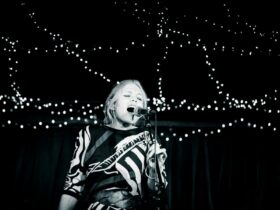 A performer singing with fairy lights behind them