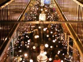 Aerial shot of chandeliers and fairylights strung high in Old Brisbane Arcade. People moving below.
