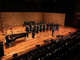 A choral group standing on stage performing
