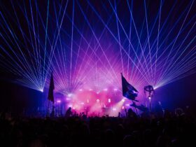 Laser beam, purple and pink stage lights, with silhouette audience