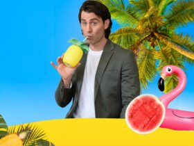 Jimmy, is dressed in a jacket, on a beach, drinking from a pineapple