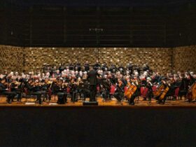 A choral group performing with an orchestra on stage