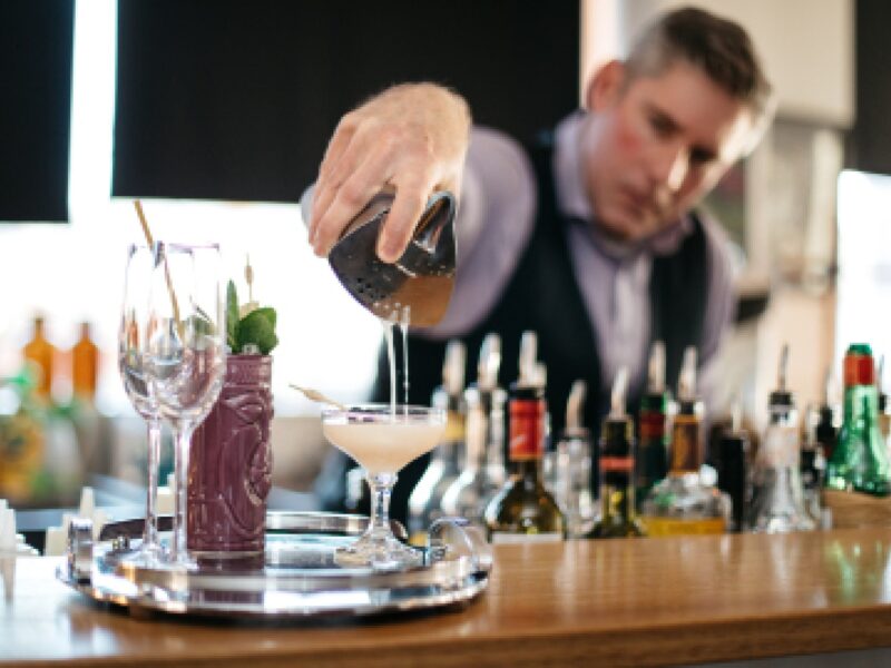A bar tender pours a cocktail
