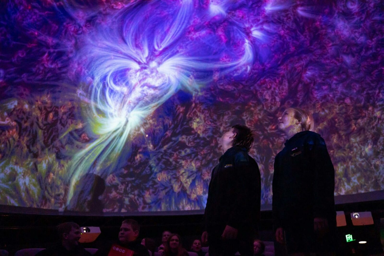 Two people standing in the planetarium during a presentation.