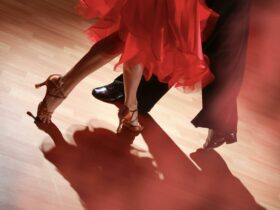 Shot of the feet of two people dancing, person in red dress and high heels and person in suit pants