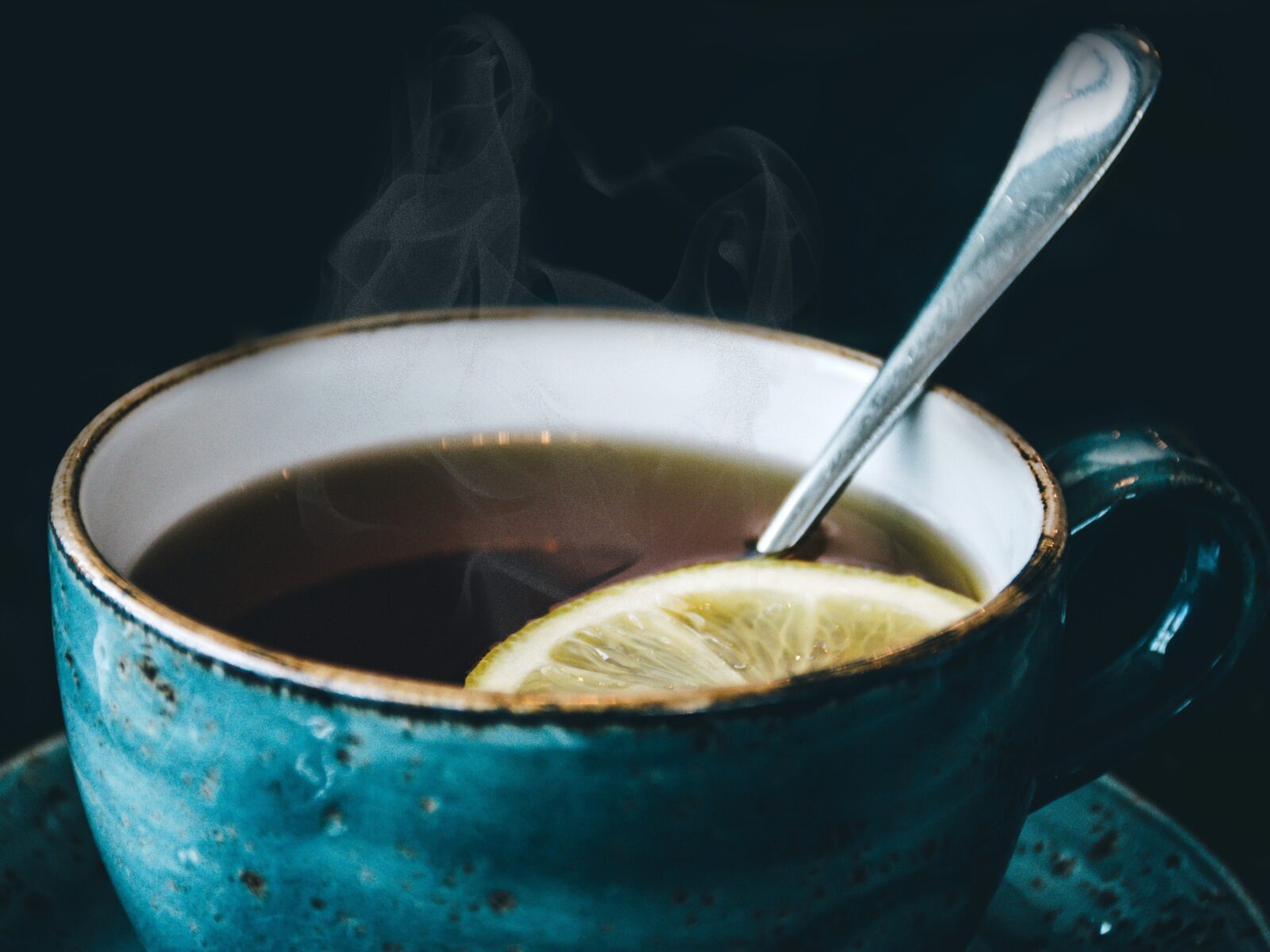 blue ceramic cup of tea with teaspoon and slice of lemon