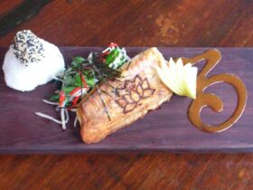 Fillet of salmon served on wooden board and spoonful of rice