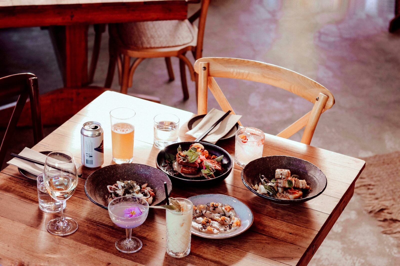 A tablescape features an array of savoury dishes, cocktails, beer and water