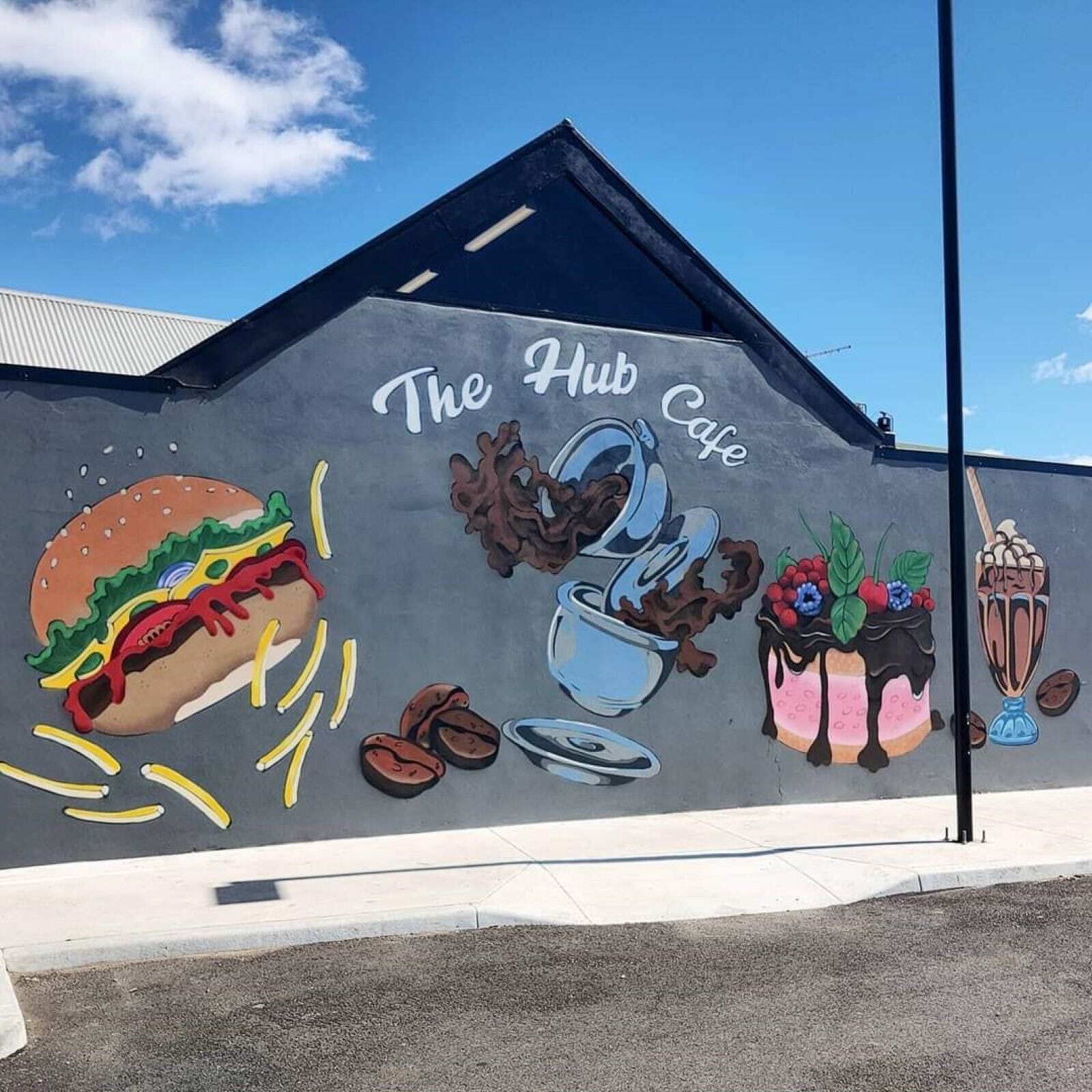 Hub Cafe side building exterior with painetd mural of hamburger cakes and coffee
