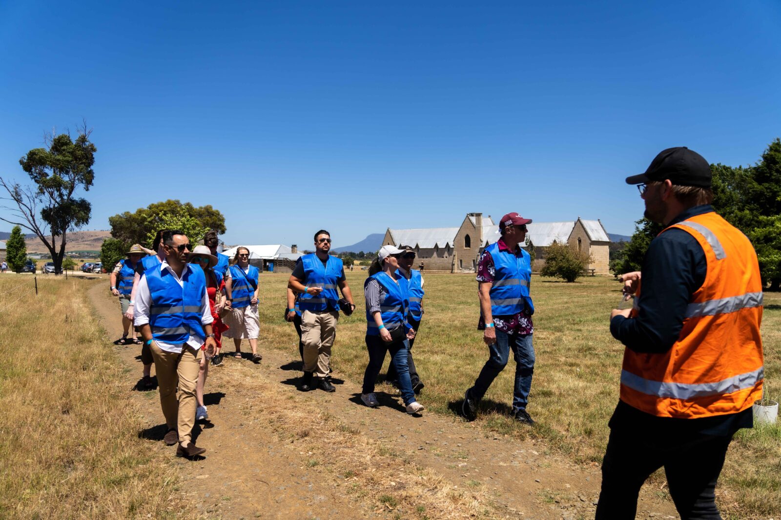 A group of people on a tour walking along a road with historic buildings in the background