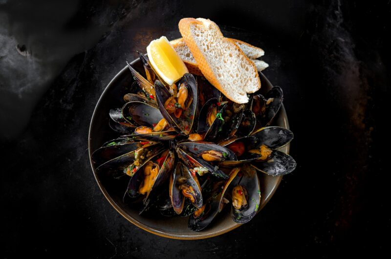A bowl of Tasmanian Freycinet Mussels, with a chilli sauce , two baguette slices and lemon