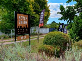 Seven Sheds driveway sign and banners saying Beer, Food and Mead, gravel driveway, trees and plants