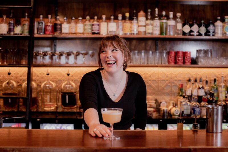 female bartender presenting cocktail in coupe glass