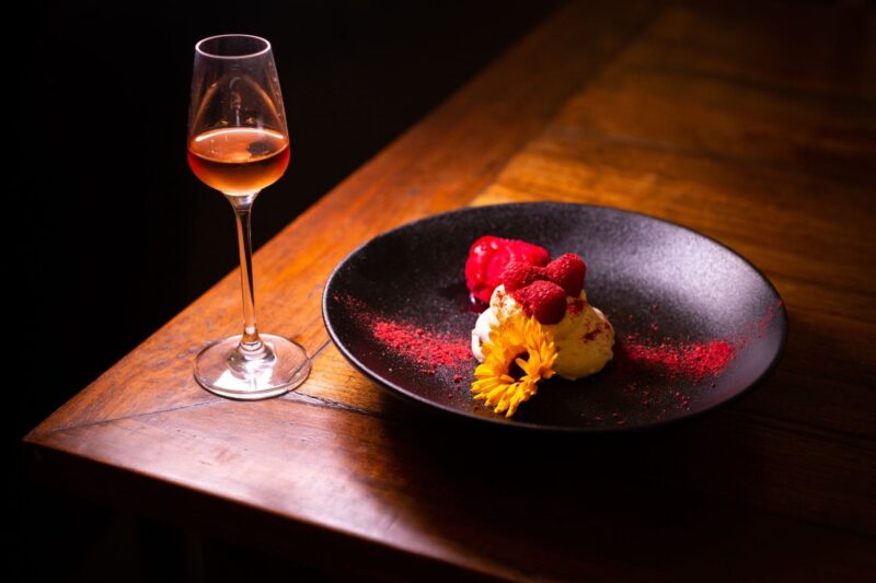 Wooden table with dessert wine glass and plated dessert with a flower