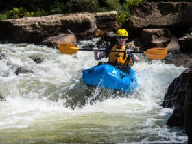 A person paddles a packraft down a rapid in Tasmania.