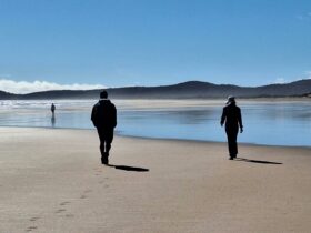Two people walking on beach withe mountain silohuette in background
