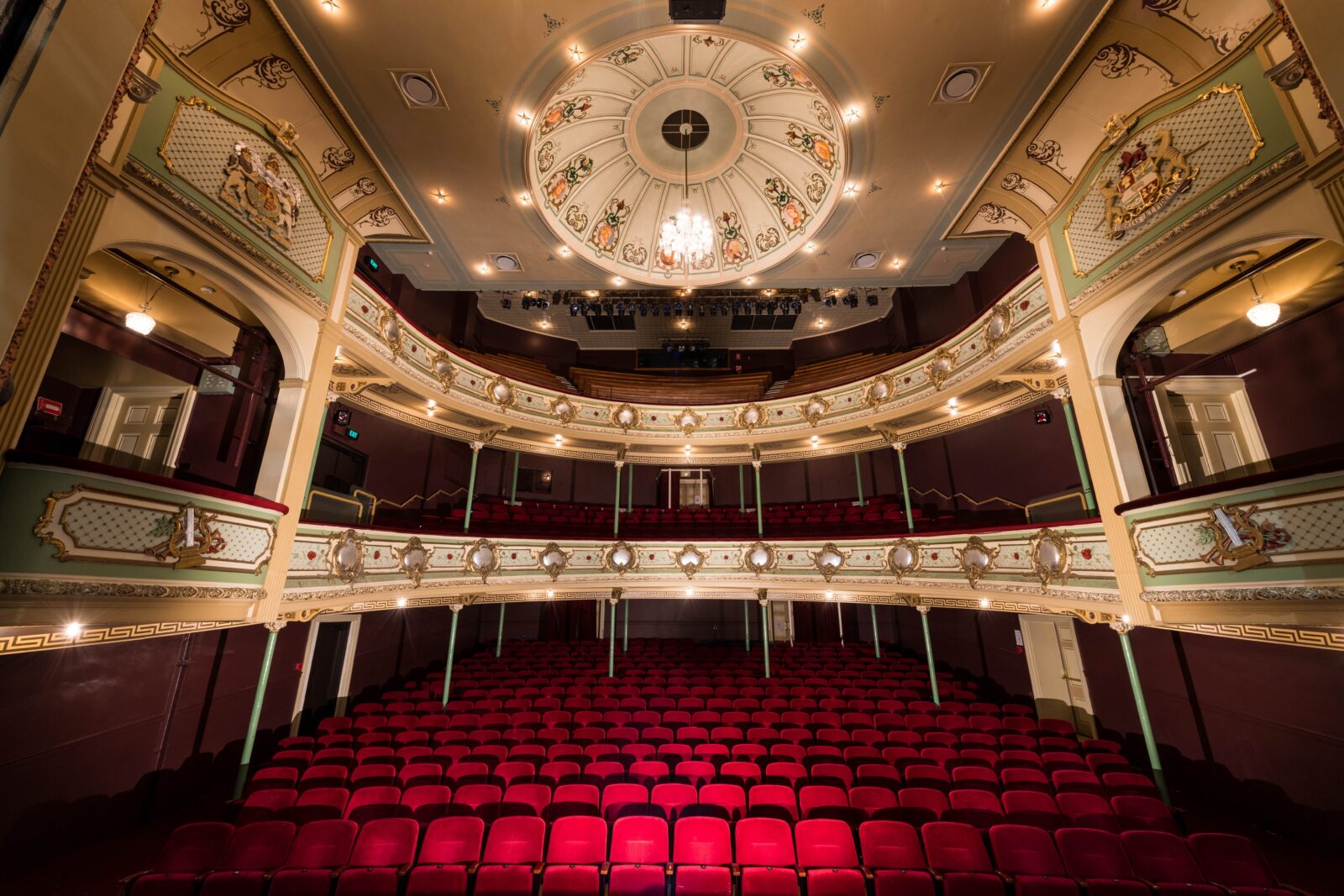 View of red velvet chairs and gold heritage balconies from the stage of the Theatre Royal