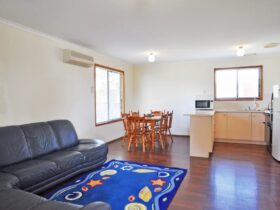 Image of beach cottage with living area with kitchen, meals and lounge combined. Timber floor.