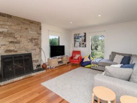 Image of upstairs lounge area with open fire, comfortable couches and tv, rug on floor and beanbags