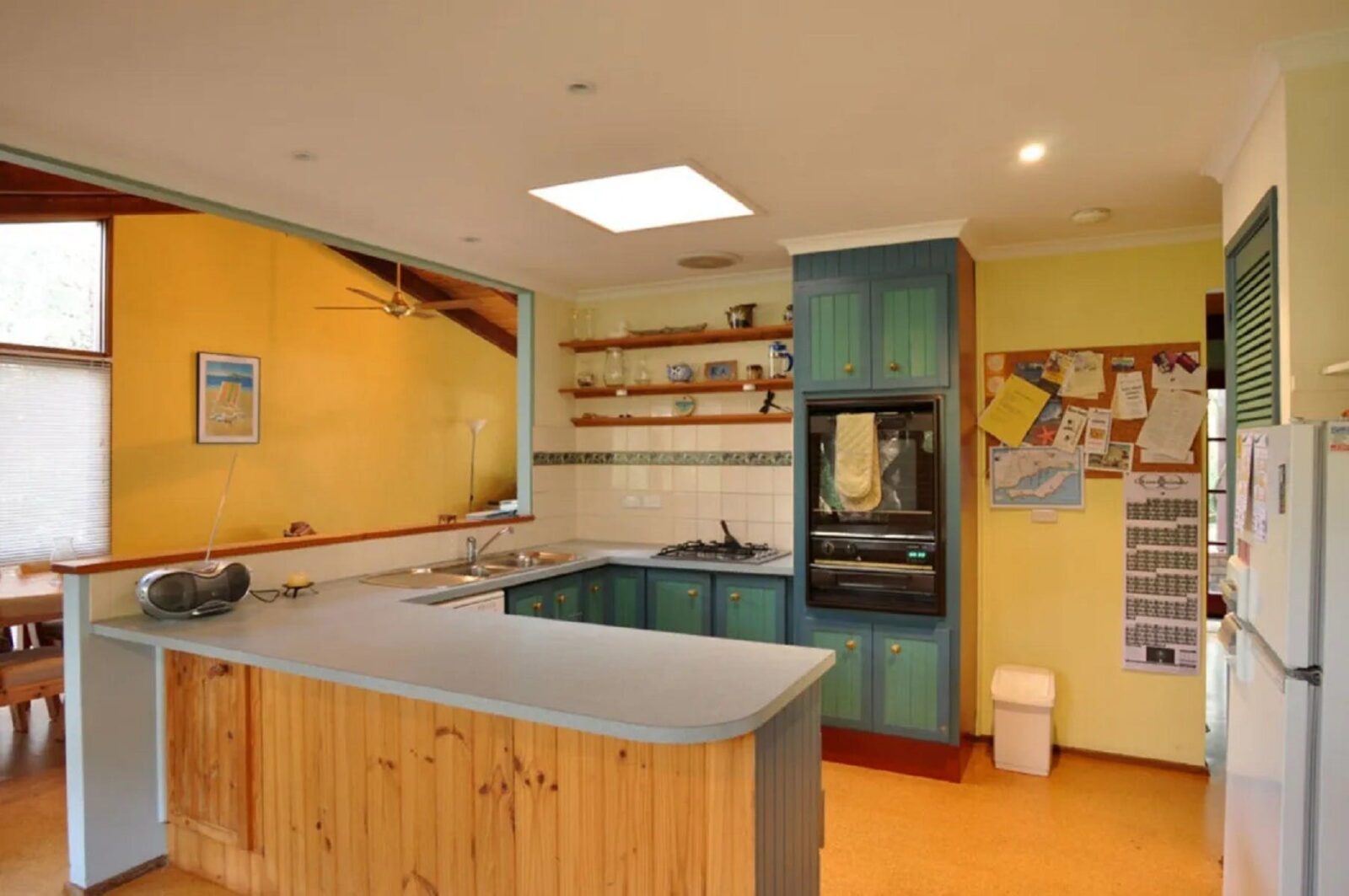 Image of old style kitchen with timber cabinets opening to living area