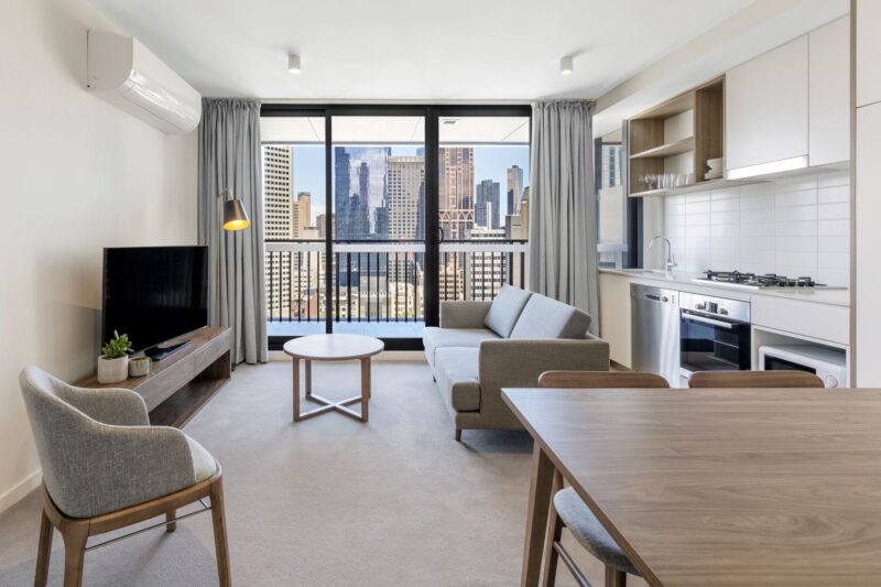 Chairs, TV and kitchen with a view of Melbourne CBD through the window