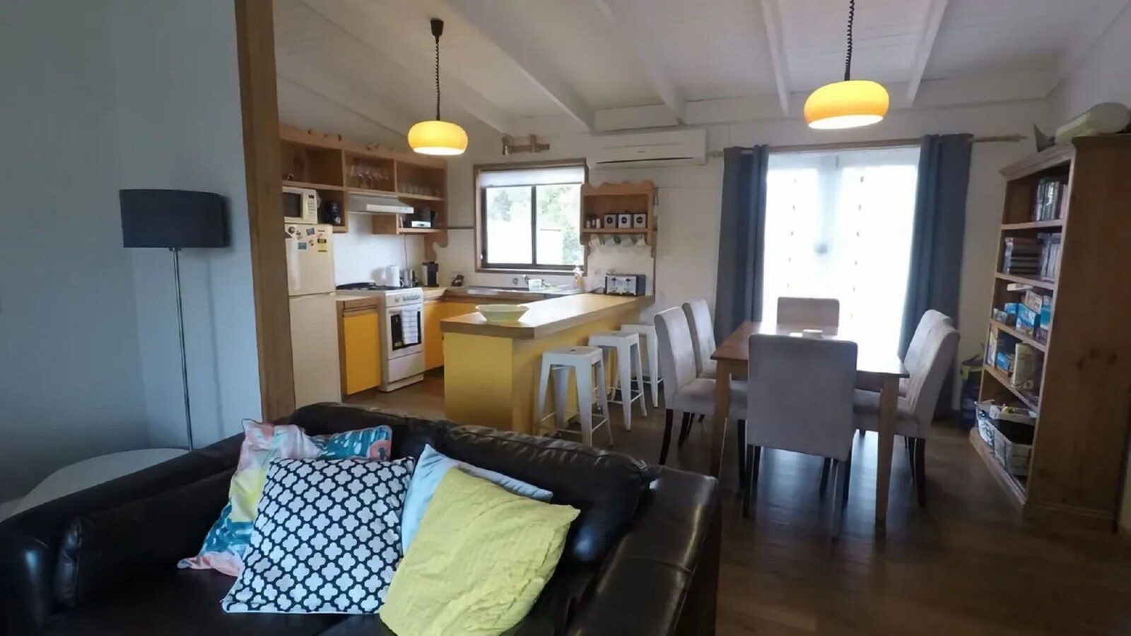 Retro style cottage with comfortable couch, table with seating for 6 and functional kitchen