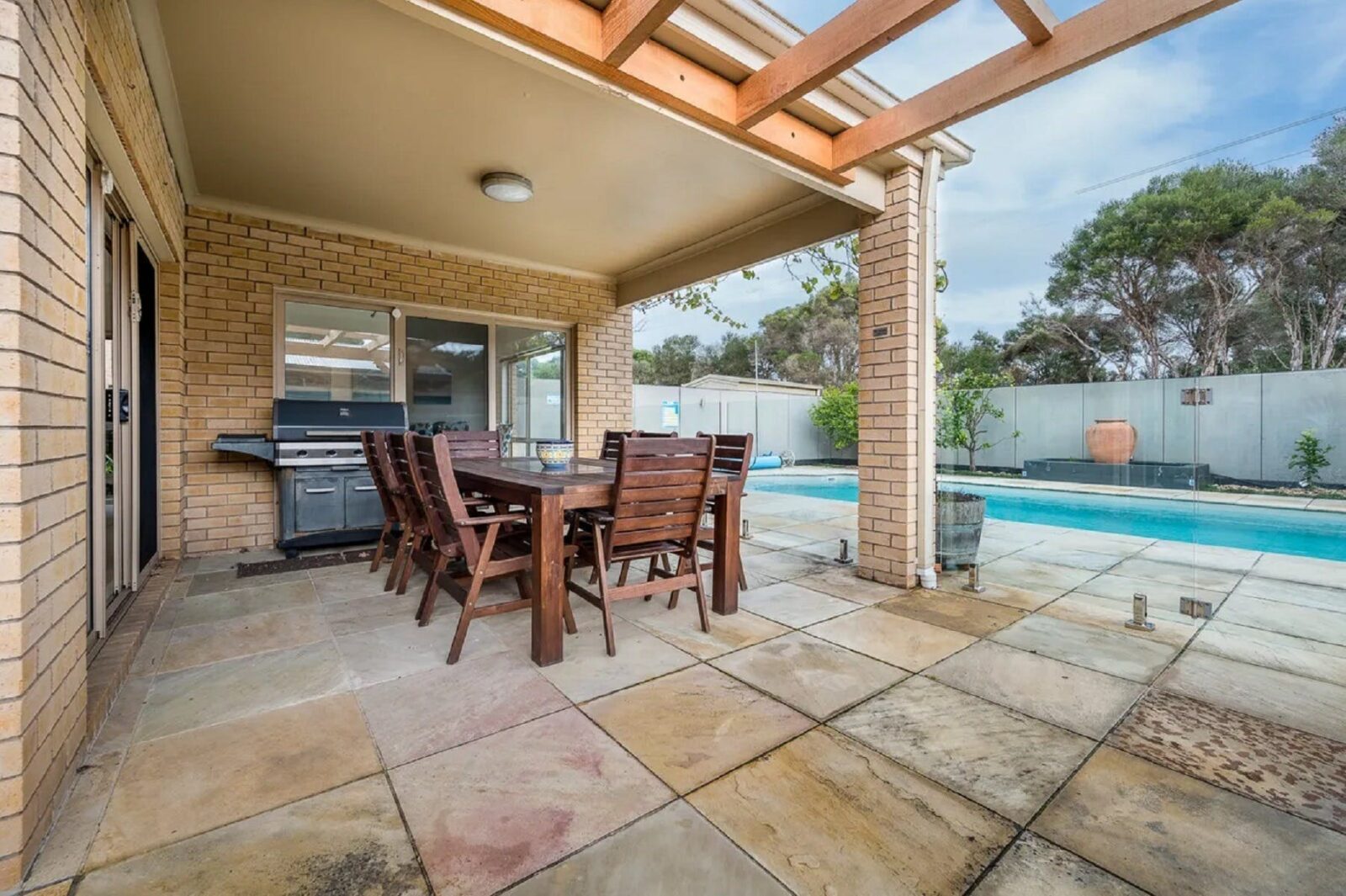 Outdoor area showing pool to right, undercover entertaining area with table for 8 & bbq