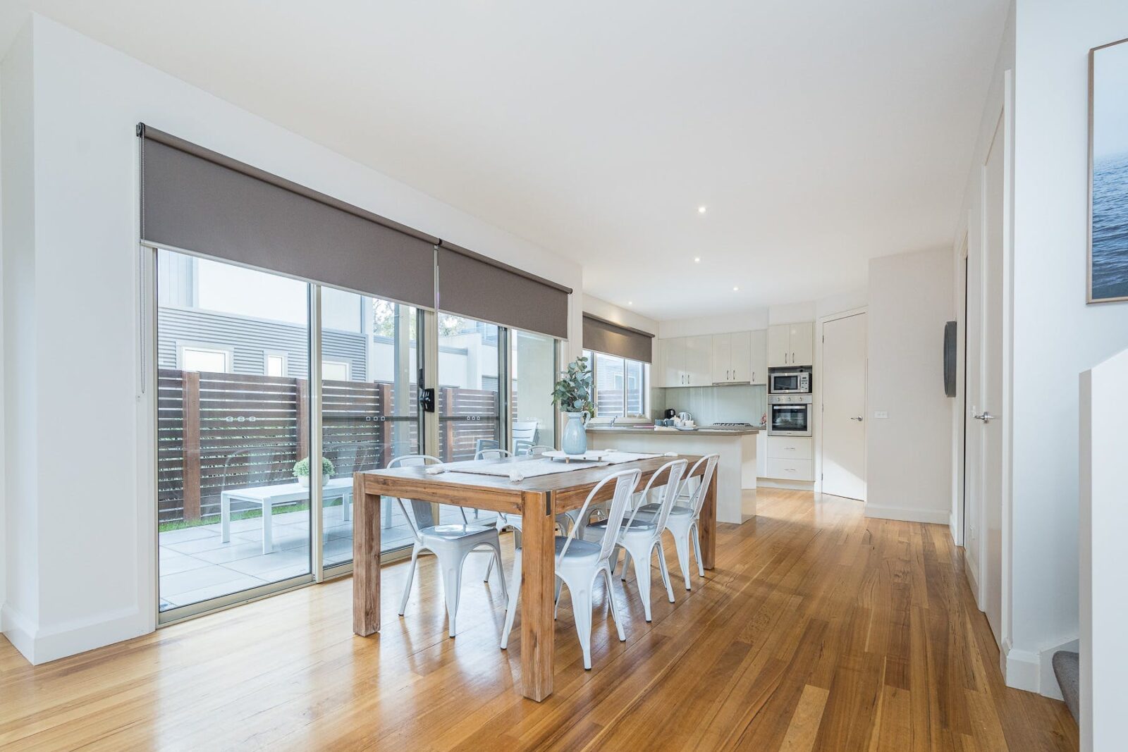 Light-filled kichen and dining area with timber floors, sliding doors leading to patio area