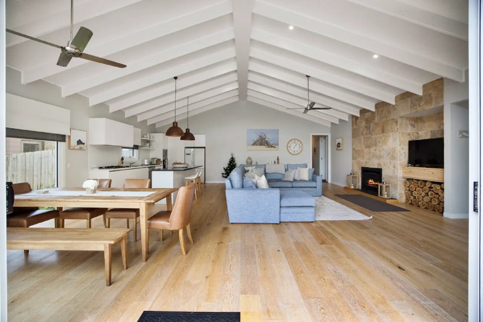 Large bright living space with exposed beams, modern kitchen, large comfortable couch & table, fans