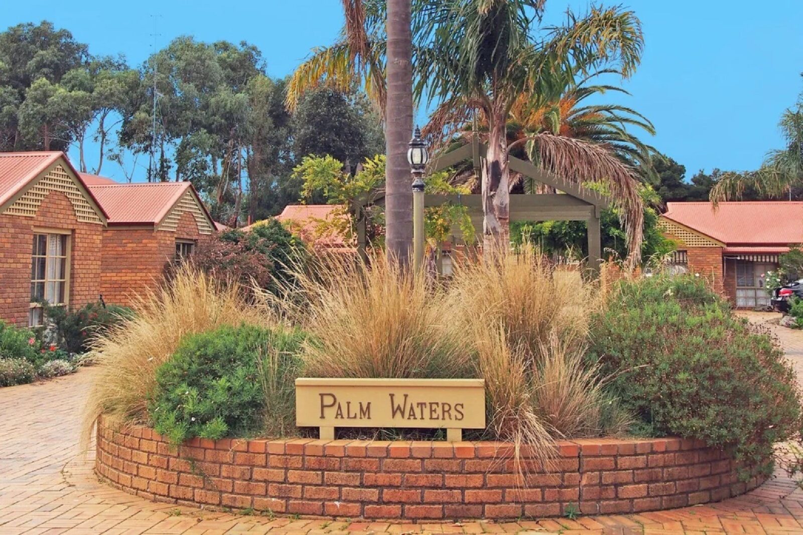 Image of front of complex containing the property Palm Waters 1, showing garden and driveway