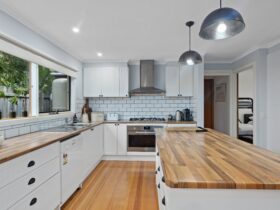 Image of kitchen with timber benchtop, timber floors, mordern appliances and white cabinets