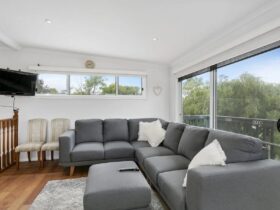 Upstairs lounge room showing large comfortable corner sofa, television & sliding glass doors to deck