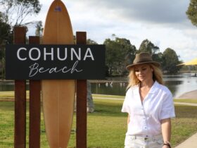 Woman in brimmed hat walking past Cohuna Beach sign