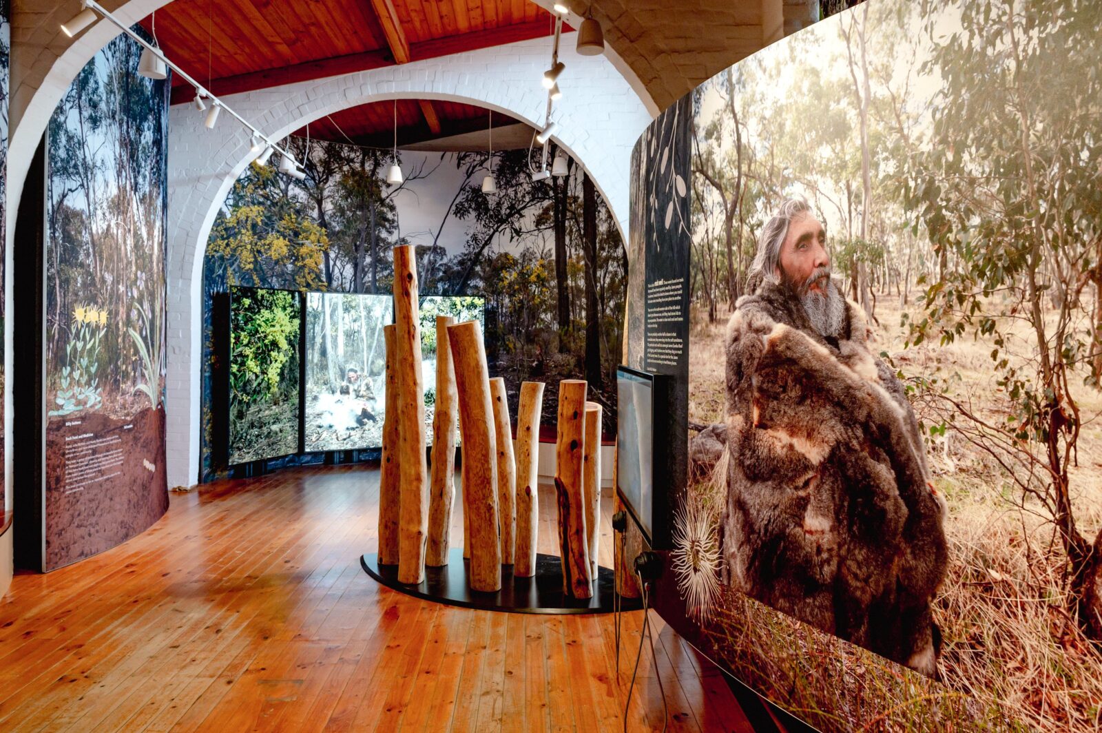 Image of exhibition showing Dja Dja Wurrung Elder Uncle Rick Nelson on a curved panel in foreground