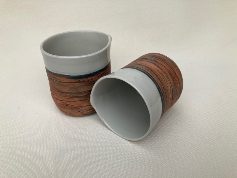Two drink beakers showing black and brown decoration