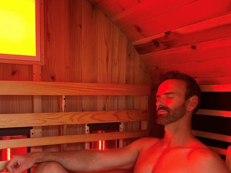 Flow Retreat guest is relaxing in a full spectrum infrared barrel sauna set in a tranquil garden