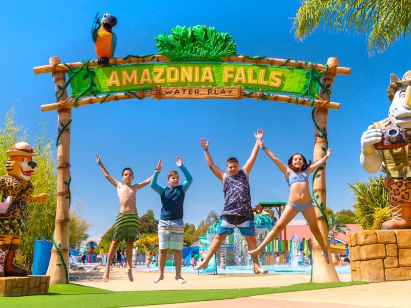 Four children jumping up to celebrate an exciting day at Funfields under the Amazonia Falls entrance