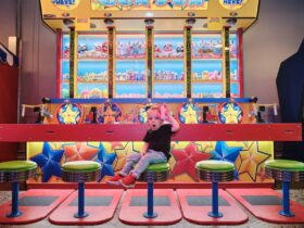 Colourful arcade game with toddler enjoying pink toy.