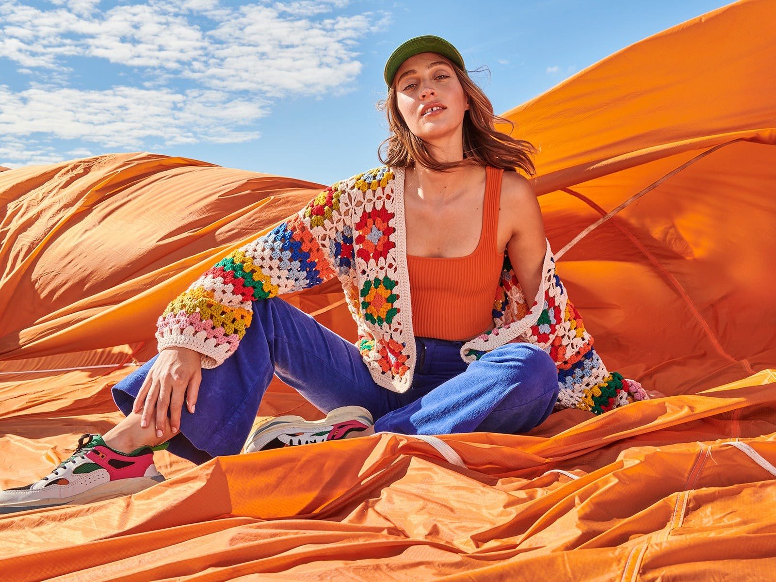 Model wears crochet cardi, cami, flares pants surrounded by parachute blowing in wind