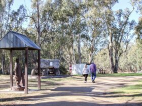 Couple walking past redgum carved statue