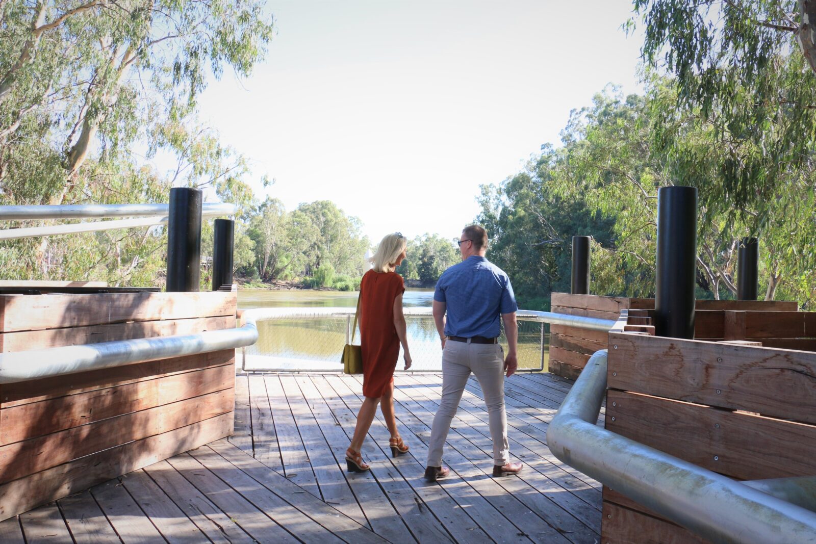 Couple walking on redgum wharf at Koondrook with Murray River in the background