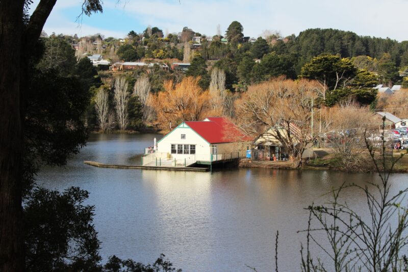 View over lake to red and white boathouse building and jetty