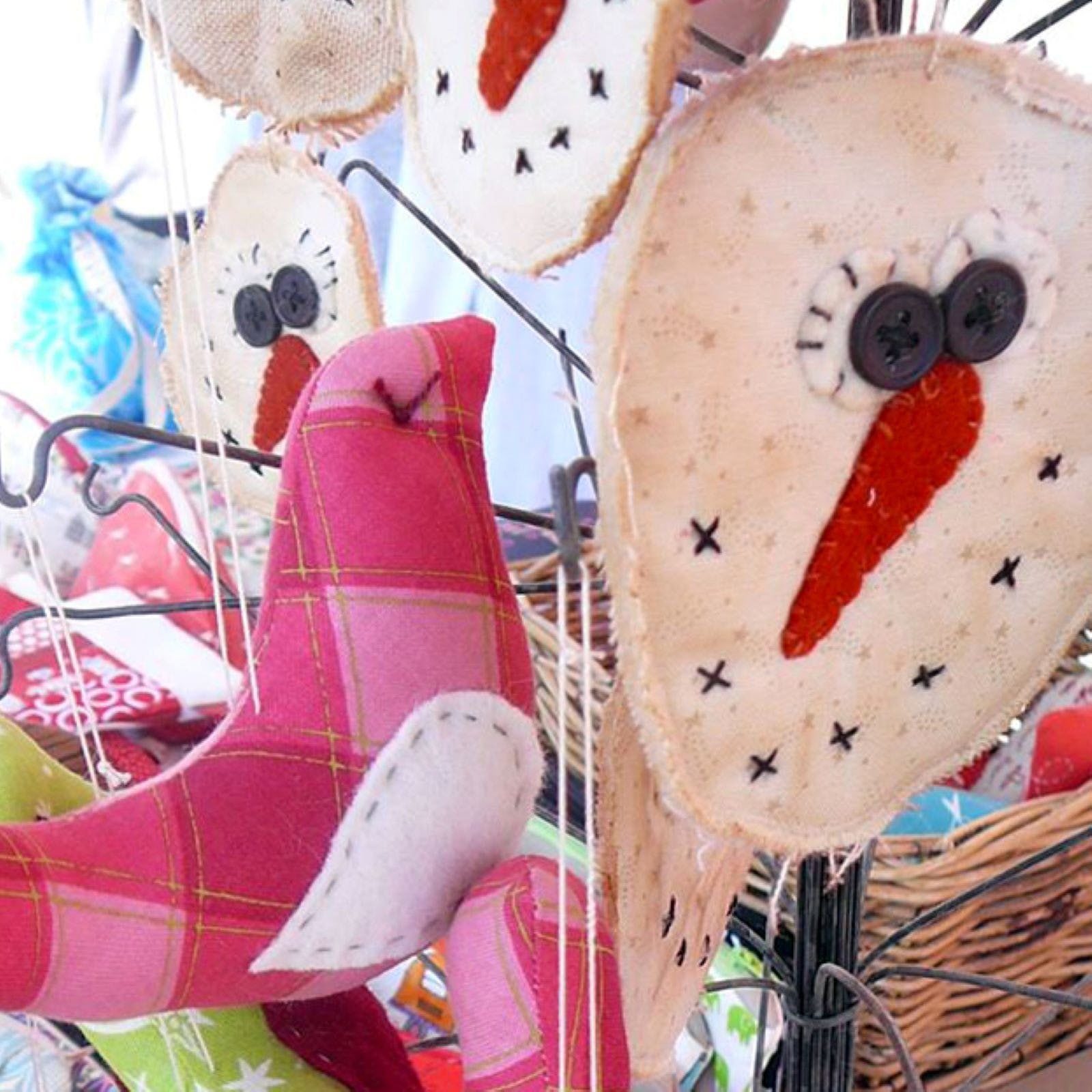 Image of handcrafted fabric pink bird in foreground and a handmade snowman face in background