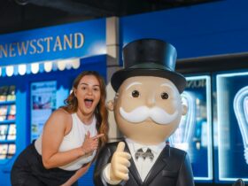 Woman points to a statue of Mr. Monopoly with a big smile on her face.