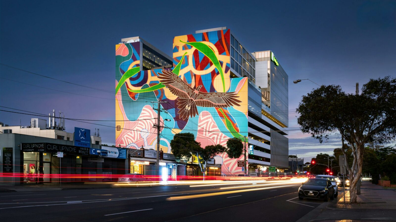 A large Indigenous mural featuring Bunjil on a building facade at night