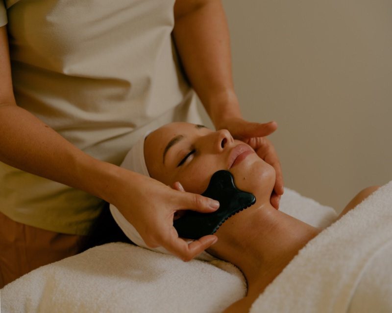 A therapist massaging the guest’s face with a guasha stone