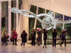 people look at a hanging mechanical sculpture in a gallery